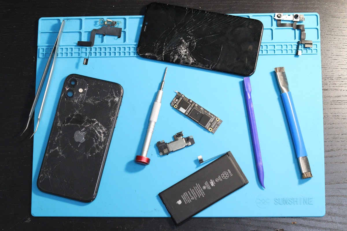 A disassembled phone laid out with repair tools on a mat, no people, for the right-to-repair piece on the bench and the software locks that distrust genuine parts
