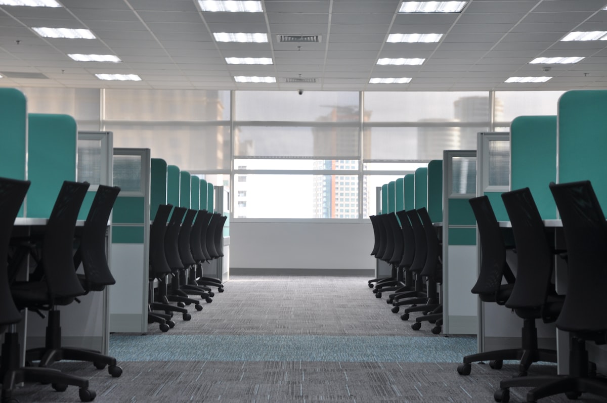 Empty rolling chairs at office cubicles, no identifiable people, for the four-day-week piece and its question of which desk workers get the day off