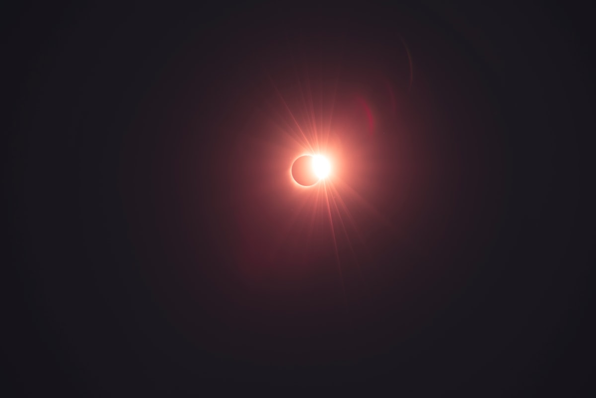 A total solar eclipse diamond-ring moment just after totality, the Sun's corona flaring around the black Moon against a dark sky, no identifiable people and no readable brands or logos, for the piece on where to watch the August 12 2026 eclipse