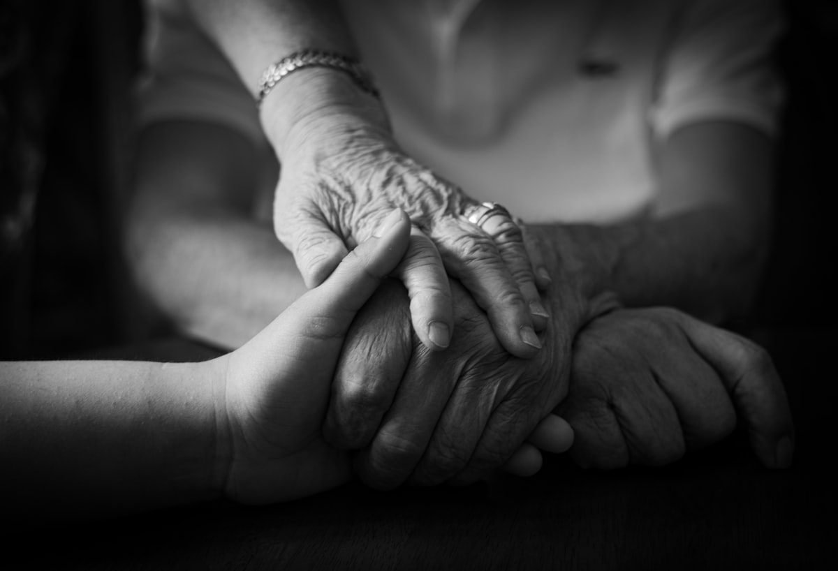 Two generic, unidentifiable hands holding each other with care, no faces shown and no identifiable person, for the piece on shrinking family networks and who is left to answer the phone; legal required a non-identifying image, not one purporting to depict Gu Bei or her mother
