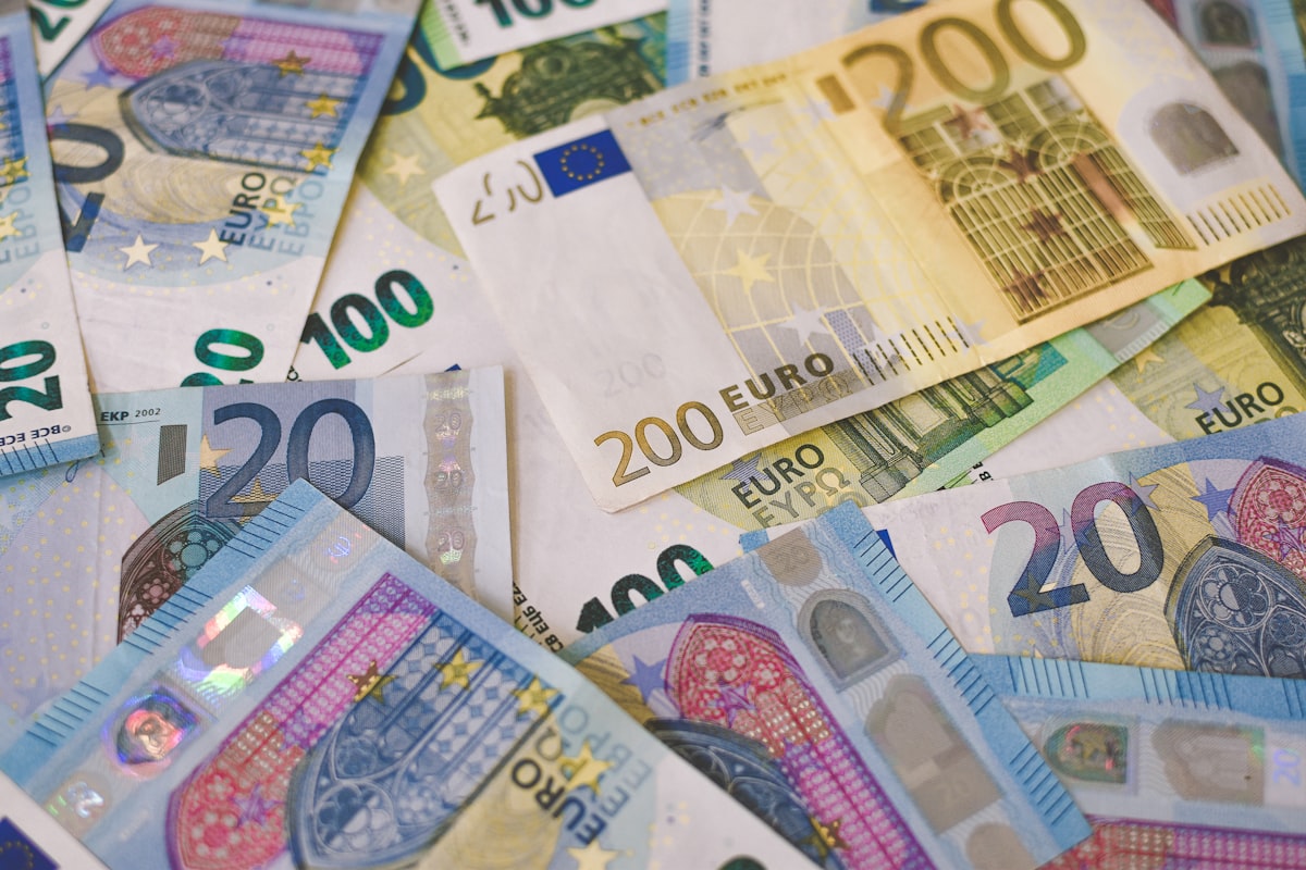 A loose pile of current euro banknotes in several denominations (20, 100, 200) on a plain surface, no identifiable person and no readable brand name or logo beyond the currency's own printed design, for the piece on the ECB's public survey over new euro banknote designs