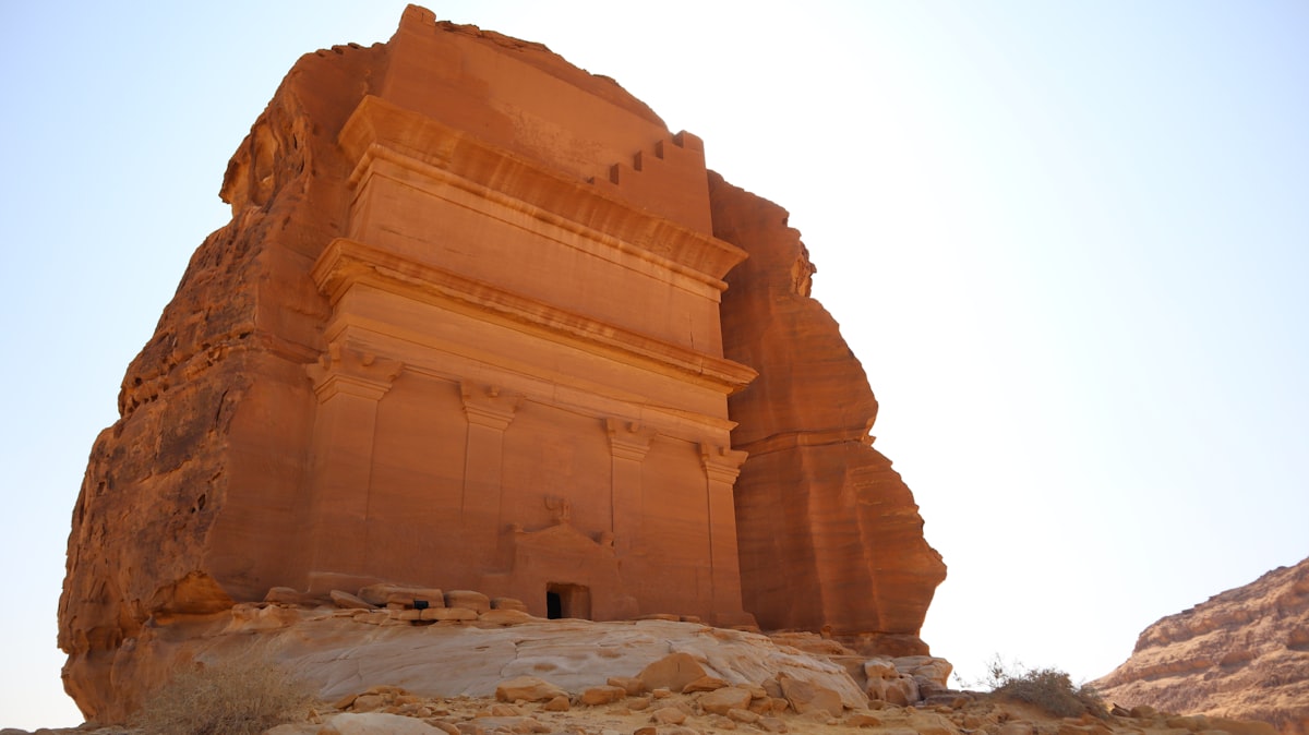 A lone Nabataean tomb standing in the open desert at Hegra (Mada'in Salih), AlUla, no identifiable people, echoing the piece's Qasr al-Farid lede