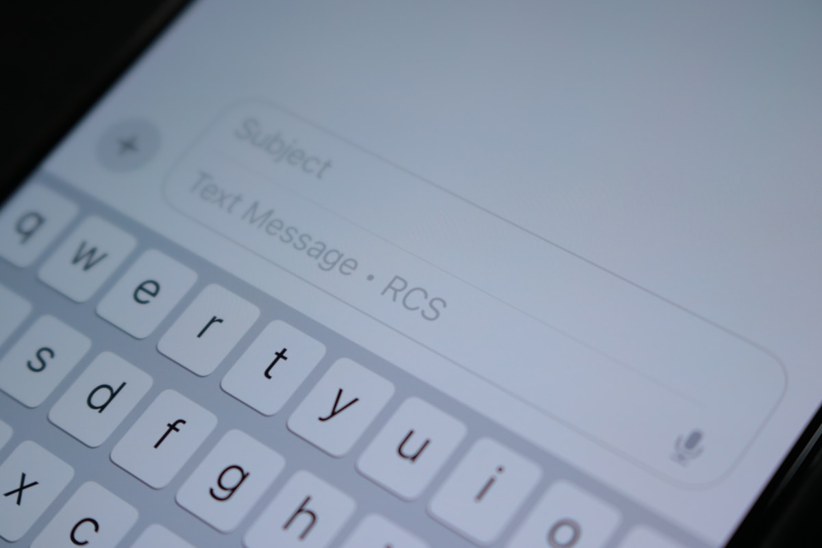 A close-up of a phone screen and keyboard mid-text, no face shown, for the piece on the group chat's unwritten etiquette code