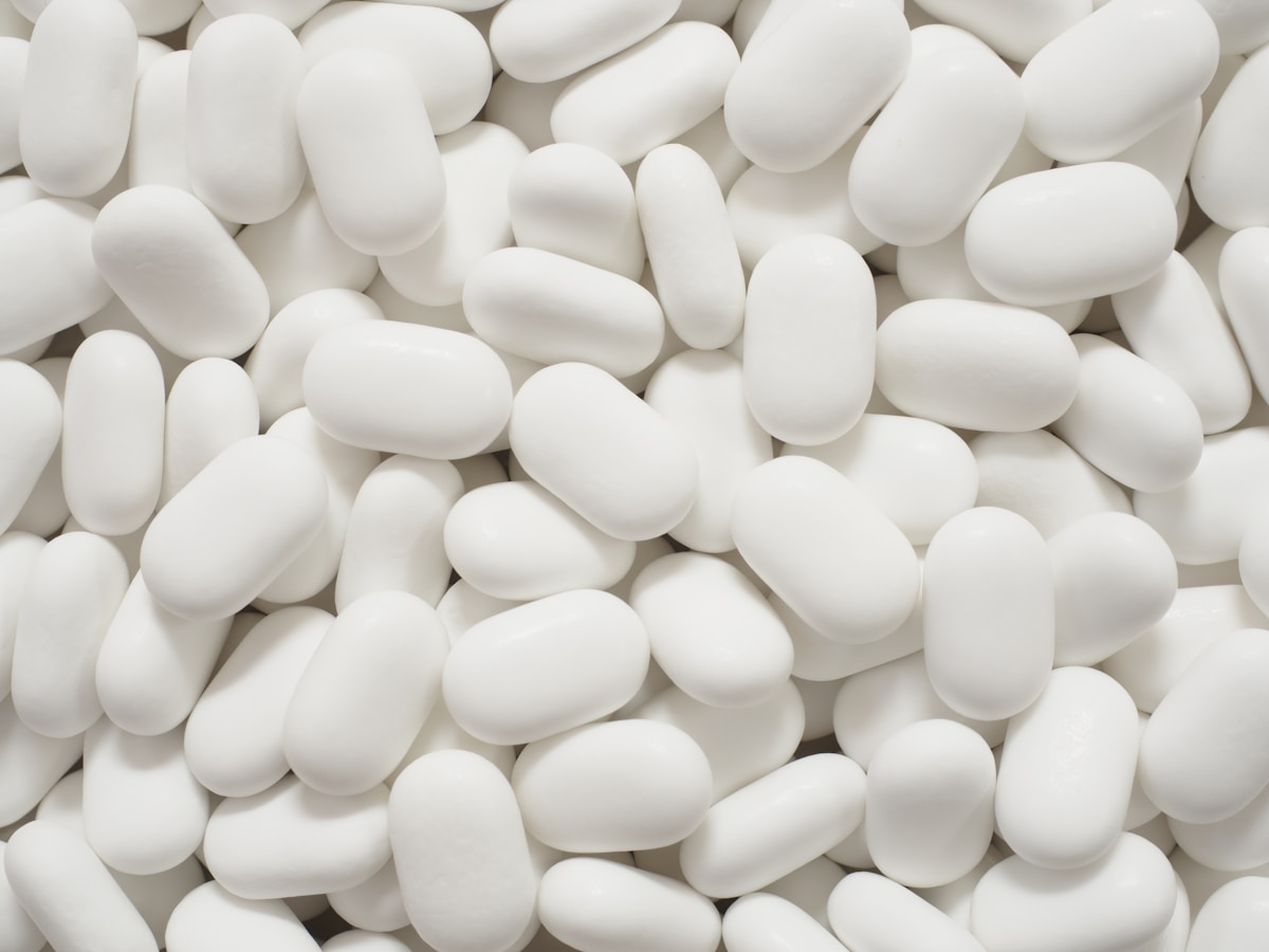 A spread of plain white oval tablets with no packaging, people, or brand, for the piece on cheap-to-make oral GLP-1 pills widening access