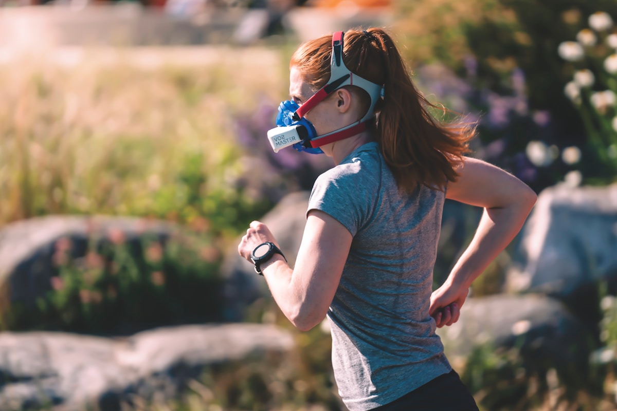 A person wearing a metabolic gas-exchange mask while exercising outdoors, the direct oxygen measurement a wrist estimate only approximates